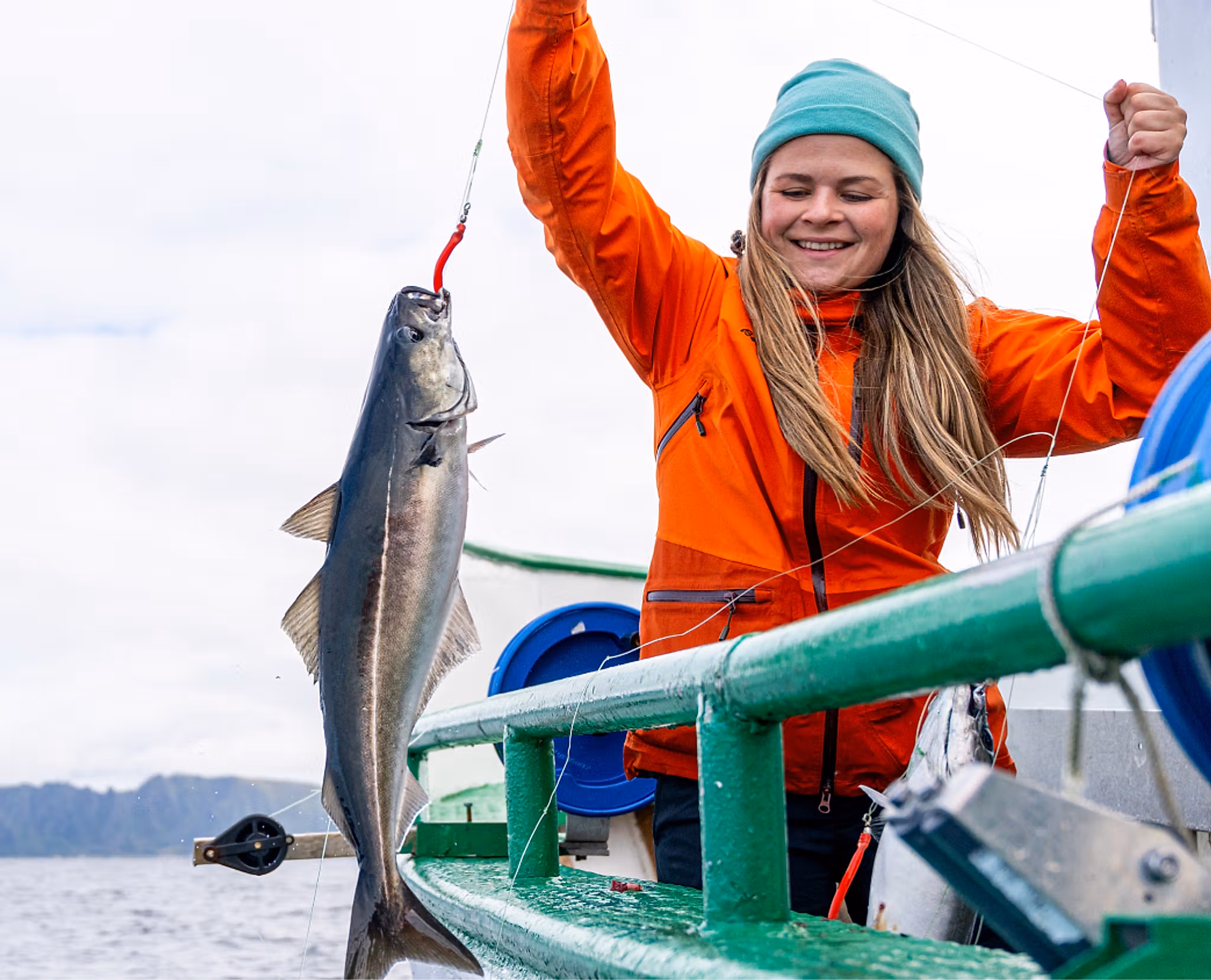 A lady pulling a fish on to a boat
