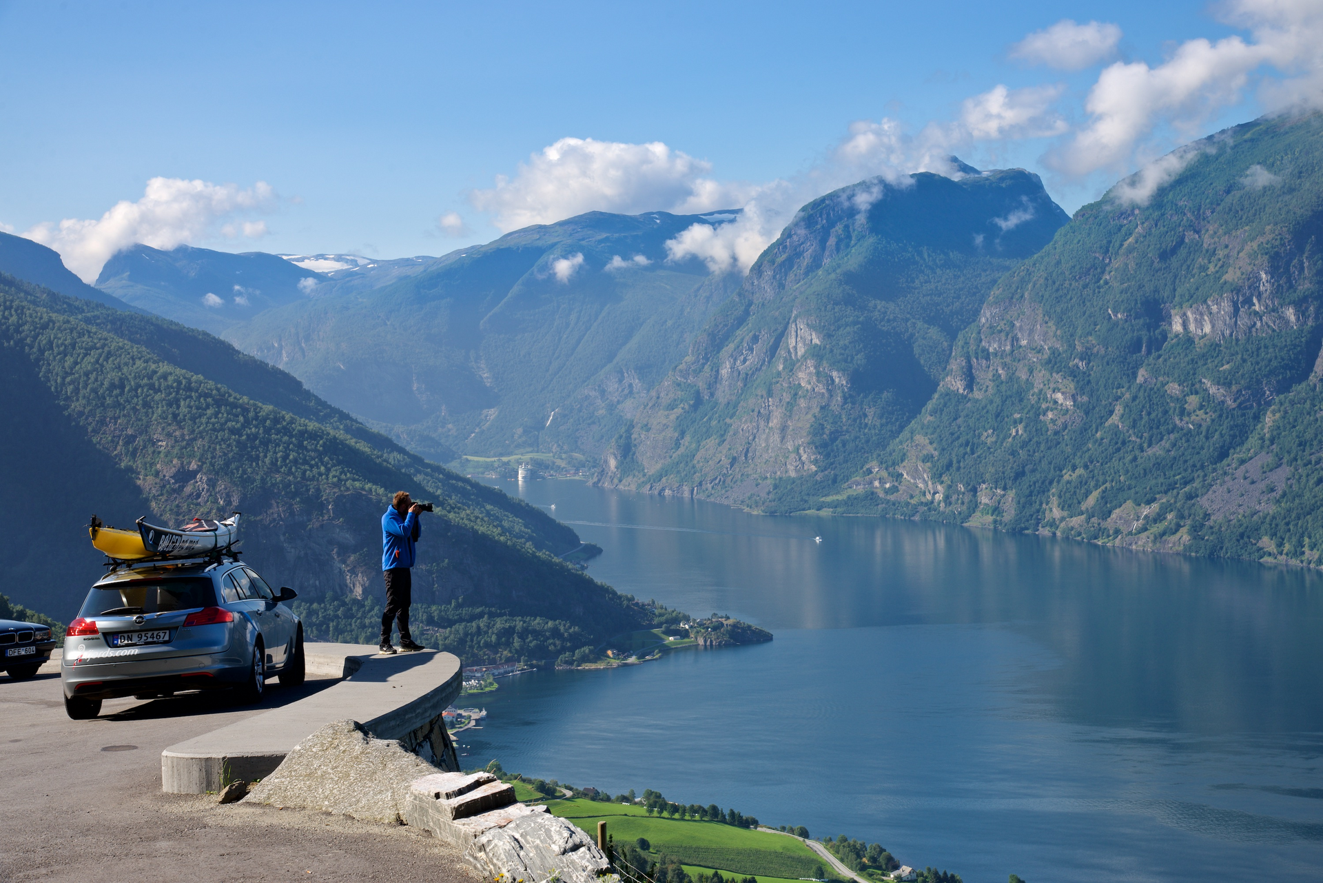 Fotograf som tar bilde av fjorden ved bilen sin
