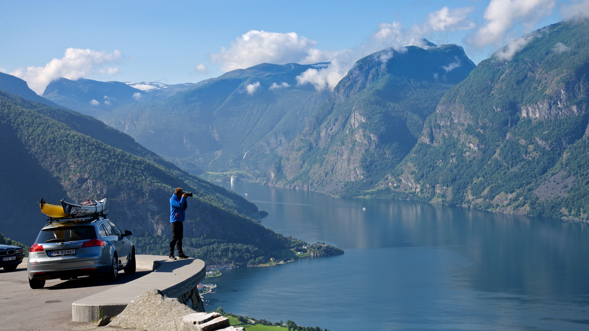 Photographer taking a picture of the fjord by his car