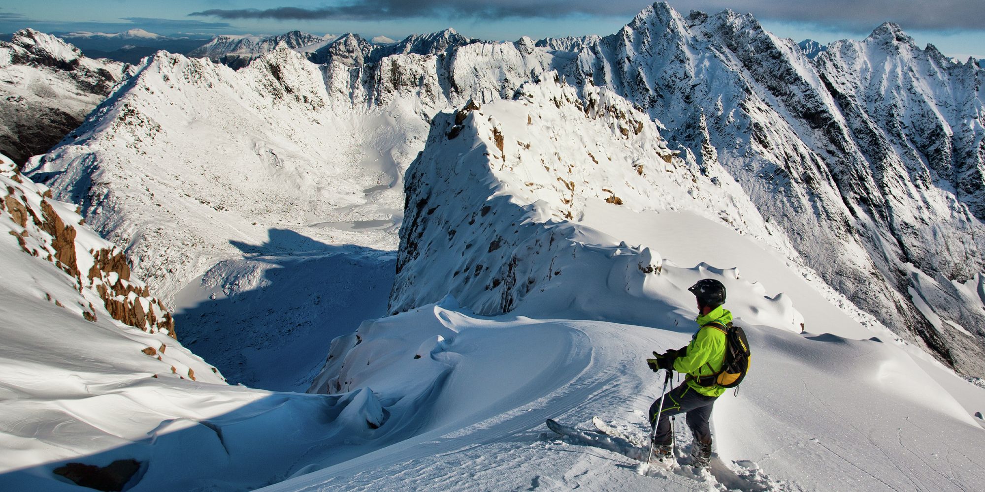 En mann på topptur på ski står klar til å kjøre nedover fjellet